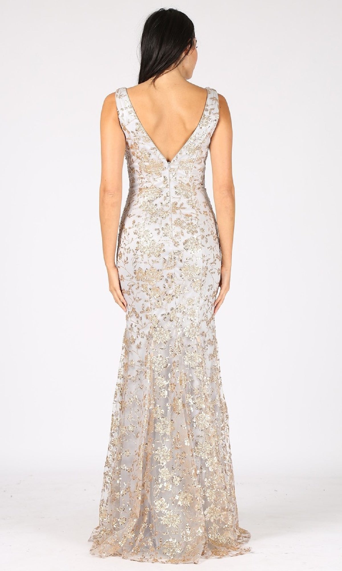 A woman wearing the Sequin-Print Long Prom Dress: Eureka 9706, a floor-length sleeveless gown with gold floral sequins and a deep V-back, stands against a plain white background.